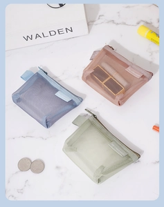 Detail of three colorful mesh coin purses in blue, pink, and green with zipper closure.