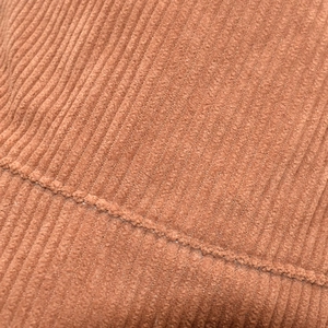 Détail du tissu en velours côtelé marron montrant la texture nervurée et les coutures