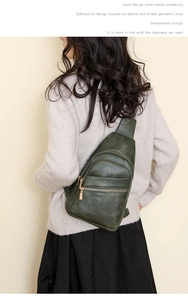 Detail of dark green PU leather chest bag with litchi texture and multi-zipper pockets