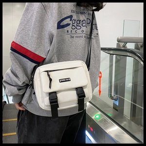 Close-up of white minimalist messenger bag with black dual buckle straps and logo detail