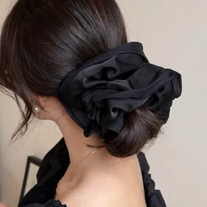 French style black satin scrunchie with large pleated floral design for elegant bun hairstyles