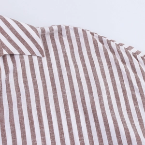 Détail du col en V et de l'épaule sur chemise en lin à rayures verticales marron