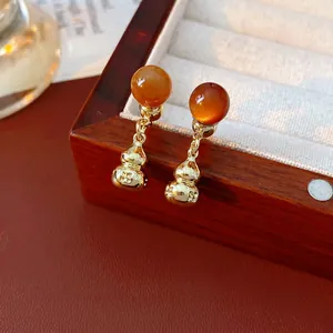 Vintage golden gourd earrings with reddish-brown beads displayed on a wooden jewelry box