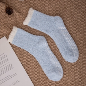 Close-up of light blue coral fleece socks with anti-slip silicone grippers on the sole