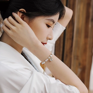 Vintage Opal-Perlenarmband mit goldenem Blumenanhänger am Handgelenk für einen edlen Look