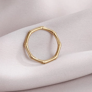 Elegant gold bamboo-style stainless steel ring on a soft lavender silk fabric background