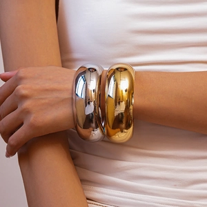 Polished silver and gold chunky metal cuff bracelets styled on model's wrist