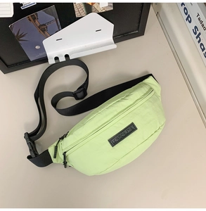 Close-up of mint green nylon chest bag with black adjustable strap and logo detail