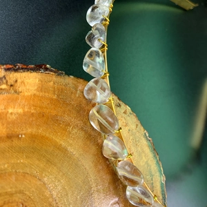 Macro shot of handmade gold wire crown featuring natural white crystal stones on wood