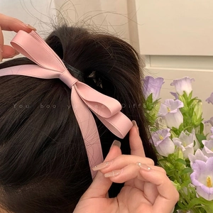 Close-up of pink satin bow hair clip with long ribbons on a high ponytail for women