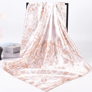 Detail of silk satin scarf showing champagne paisley pattern and premium draped texture