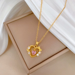 Macro detail of gold-plated heart necklace with pink gem and bow on silk fabric