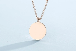 Detailed close-up of rose gold coin pendant necklace with polished bead chain on blue background