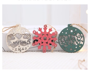 Three wooden Christmas ornaments with reindeer and snowflake motifs on white fabric background