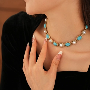 Detail of vintage necklace with turquoise and pearls on gold base worn by a model