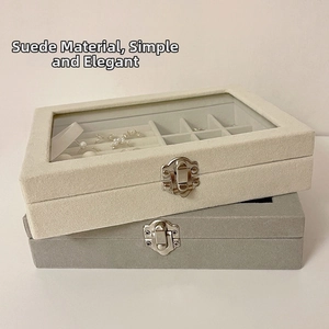 Macro detail of velvet jewelry boxes with transparent lids and metal clasps in beige and grey