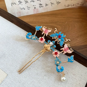 Détail de l'épingle à cheveux avec papillon en émail bleu, fleur et pompon perle