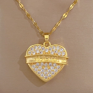 Macro detail of a gold heart pendant with white crystals and MAMA engraving on a link chain