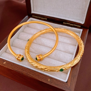 Gros plan de bracelets en or vintage avec des gravures en relief et des pierres colorées