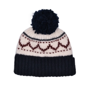 Détail du bonnet en tricot vintage montrant des motifs tissés et un pompon bleu marine