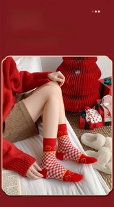 Detail of red and white checkered socks with festive gold icons in a premium gift box