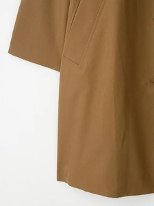 Detail of high-density twill fabric stitching on a brown trench coat pocket and cuff