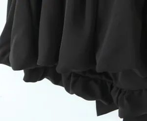 Close-up of black ruched fabric texture and double-layer pleated hem design detail