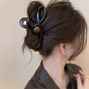 Pince à cheveux mate marron café avec ornement boule sur une coiffure chignon