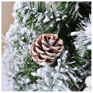 Macro view of artificial pine cone with faux snow coating and green needles for Christmas
