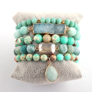 Detail of bohemian stackable bracelets with mint green beads and raw blue crystal