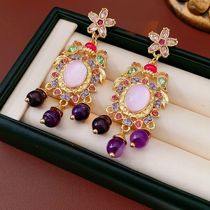 Detail of vintage gold flower earrings with pink gemstone and purple bead tassels
