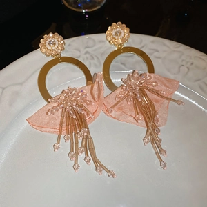 Detail of pink fabric flower earrings with crystal tassels on a white ceramic plate