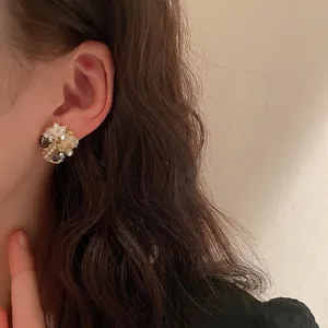 Elegant crystal flower stud earrings with resin petals and pearls on a female model