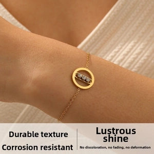 Detail of a gold chain bracelet with a circular pendant and three sliding crystals