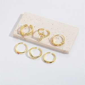 Detailed view of six gold-plated cross rings with zircon stones on a stone slab