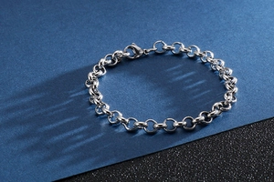 Close-up of a minimalist silver stainless steel O-chain bracelet on a dark blue background