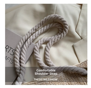 Detail of the woven shoulder bag featuring thick cotton rope handles and metal eyelets