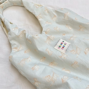 Detail view of cotton shopping bag with cute orange cat prints and brand logo label