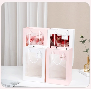 Detail of pink and white gift bags with transparent window showing floral arrangement