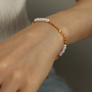Minimalist freshwater pearl and faceted gold bead bracelet worn on a woman's wrist