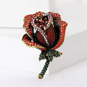 Detailed view of an elegant rose brooch featuring red rhinestones on a gold metal base