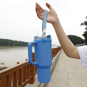 Outdoor hand-held 40oz tumbler with a blue and white braided paracord carry handle strap