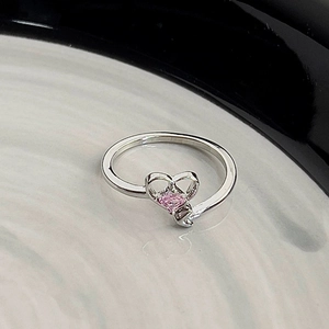 Macro shot of silver ring with pink heart-shaped zircon and hollow heart-shaped design