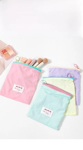 Macro shot of macaron-colored makeup pouches with ring zippers on white background
