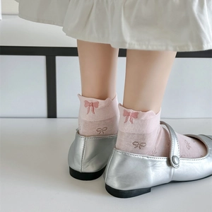 Close-up of pink cotton socks with bow embroidery and silver Mary Jane shoes