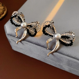 Macro view of bowknot earrings with pearls, crystals, and flowing silver tassels