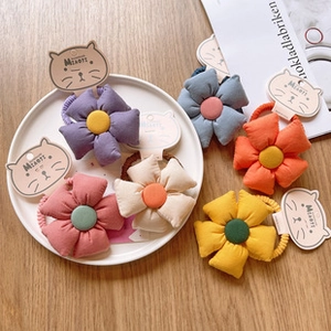 Detail of six colorful floral hair ties on display cards over a rustic wooden surface