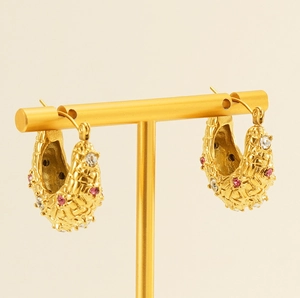 Detailed shot of C-shaped 18K gold earrings with woven texture and colorful gemstones