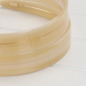 Detail of 2.2cm beige acetate headband showing glossy texture and inner metal frame