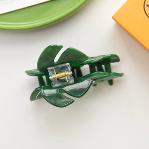 Macro shot of leaf-shaped green acetate hair claw clip with marble texture and gold spring
